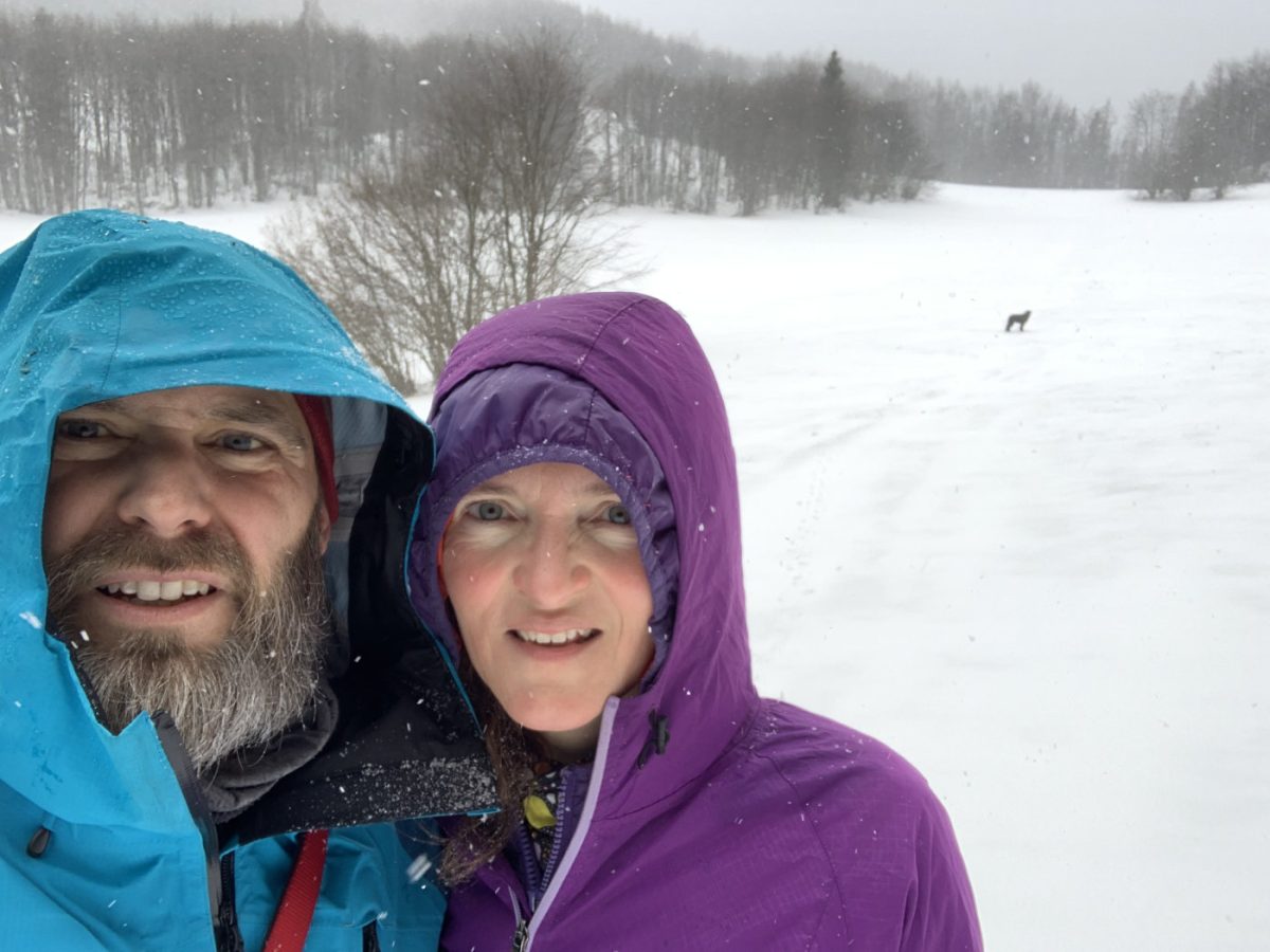 a couple and a dog in a winter meadow
